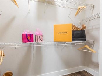 Closet with white shelves and a yellow and pink box on a white shelf at Highline Urban Lofts in Cypress, TX